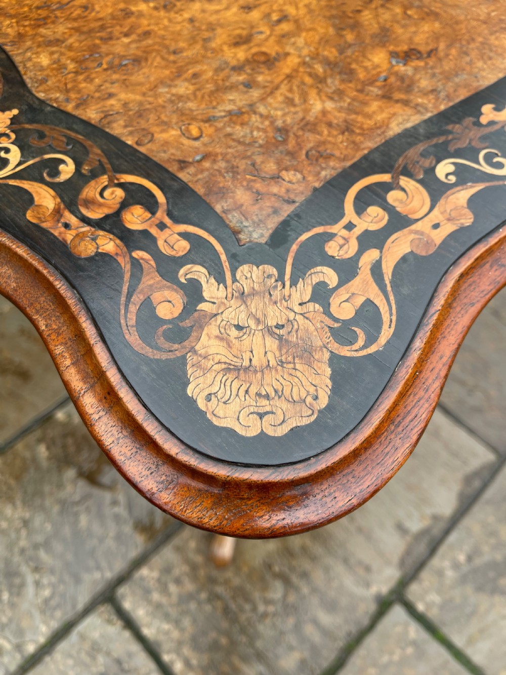 A nineteenth-century burr walnut occasional table featuring a shaped top with intricate floral marquetry, supported by a central barley twist column and a tripod base. View VII