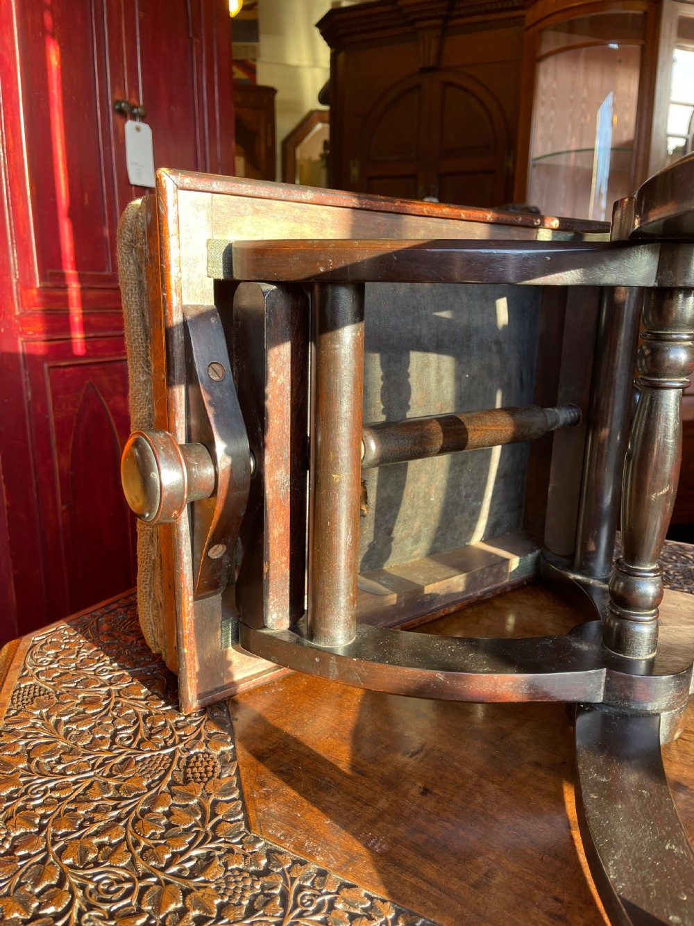 Victorian Aesthetic Movement ebonised x-frame stool featuring incised circular motifs, side adjustment knobs, and a neutral fabric seat. View II