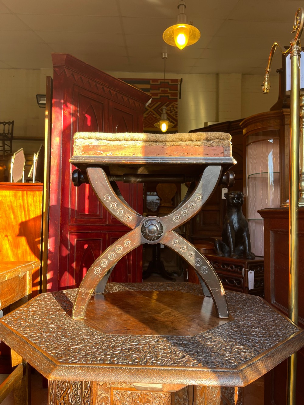 Victorian Aesthetic Movement ebonised x-frame stool featuring incised circular motifs, side adjustment knobs, and a neutral fabric seat. View III