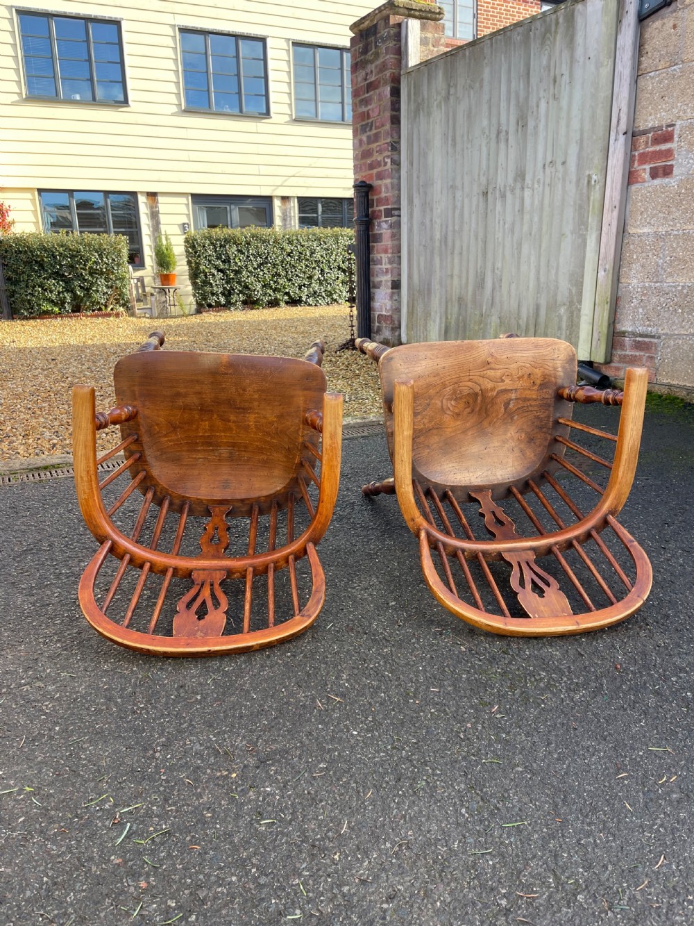 A pair of warm brown wooden Windsor armchairs featuring hoop backs, pierced central splats, turned legs, and curved stretchers. View II