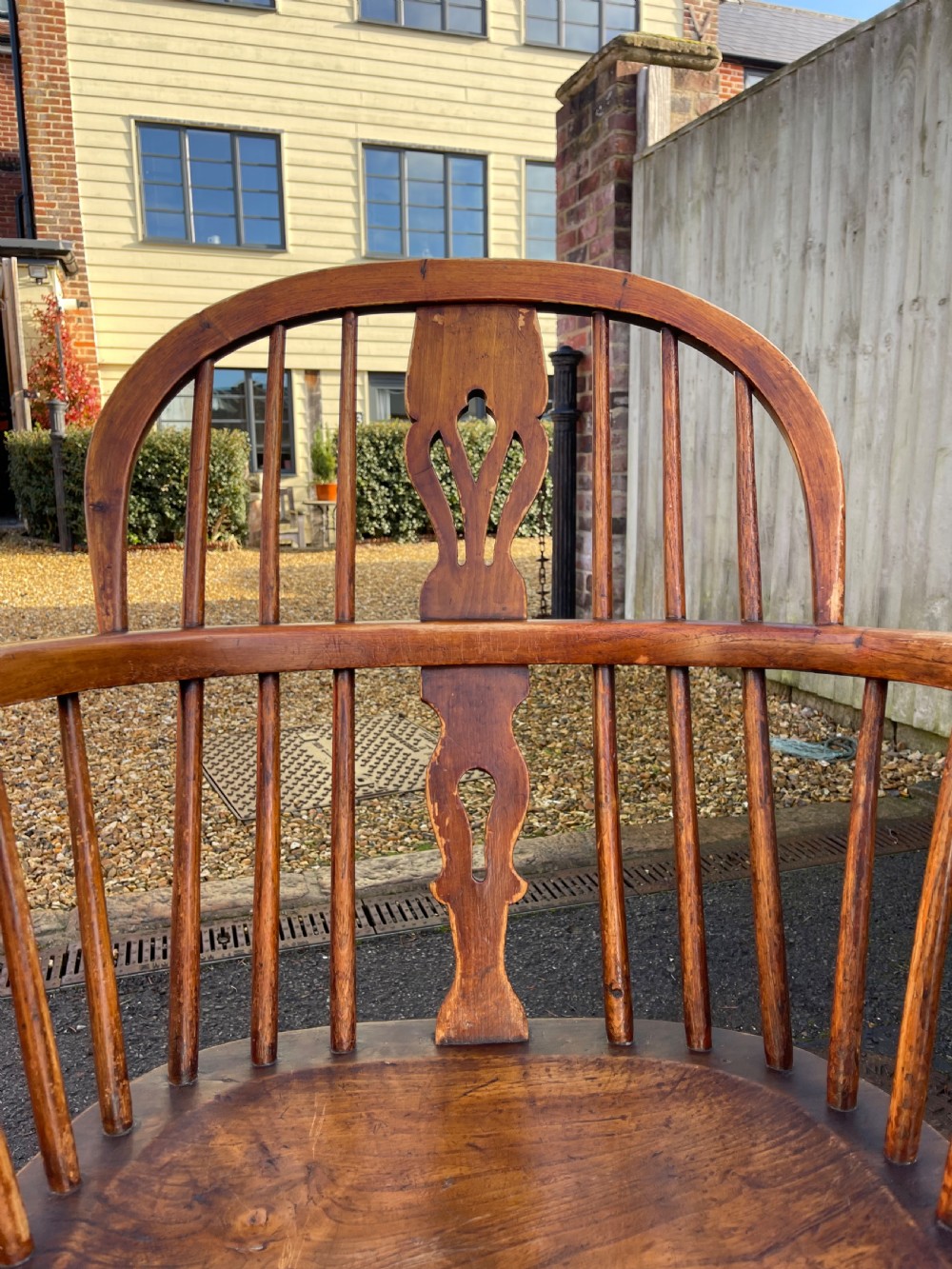 A pair of warm brown wooden Windsor armchairs featuring hoop backs, pierced central splats, turned legs, and curved stretchers. View III