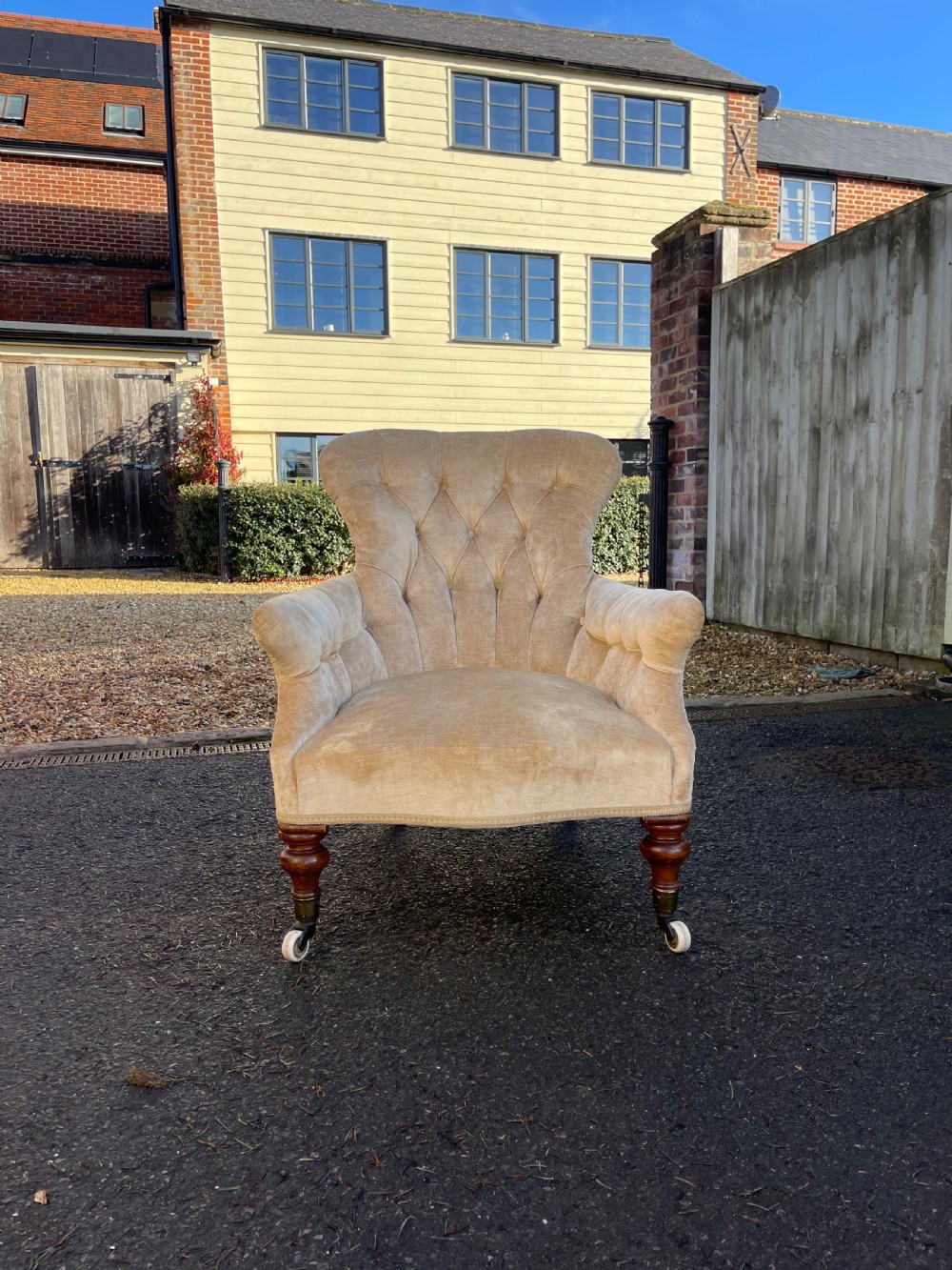 A nineteenth-century Victorian button-back armchair upholstered in beige velvet with scroll arms and turned mahogany legs on white castors. View III