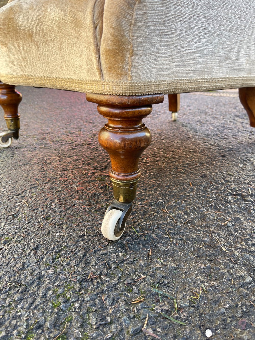 A nineteenth-century Victorian button-back armchair upholstered in beige velvet with scroll arms and turned mahogany legs on white castors. View VI