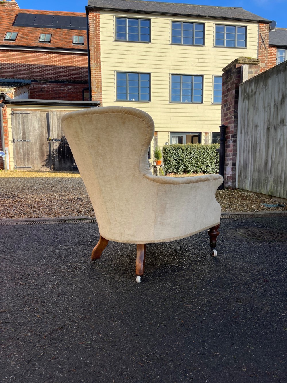A nineteenth-century Victorian button-back armchair upholstered in beige velvet with scroll arms and turned mahogany legs on white castors. View VII