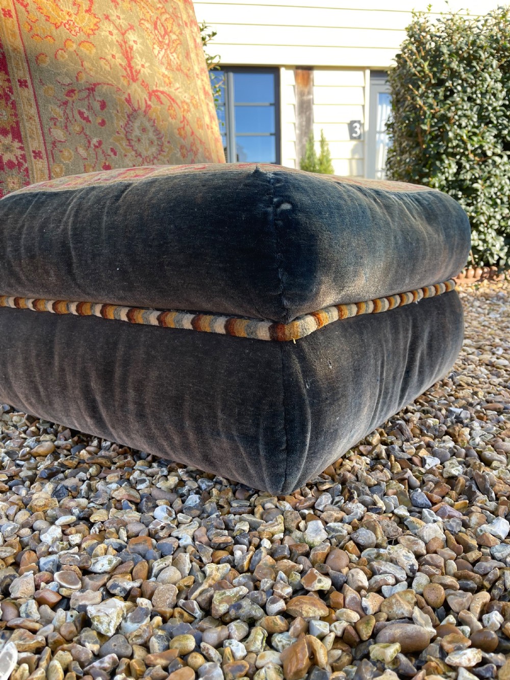 An armless slipper chair upholstered in dark charcoal velvet with a central panel featuring a red and gold oriental carpet pattern. View V
