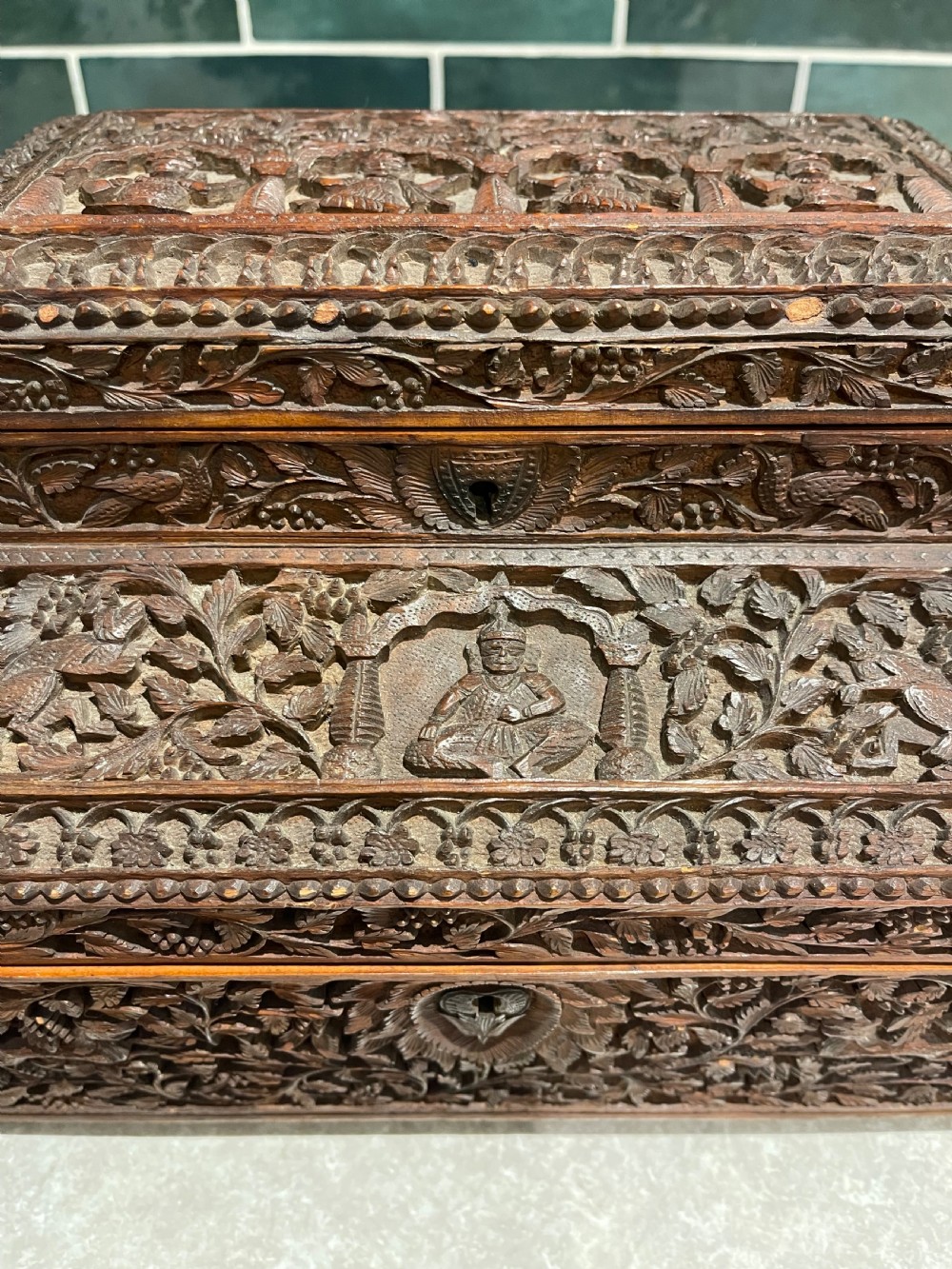 An intricately carved brown sandalwood jewellery box with a stepped lid, brass side drop handles, and brass claw feet. View III