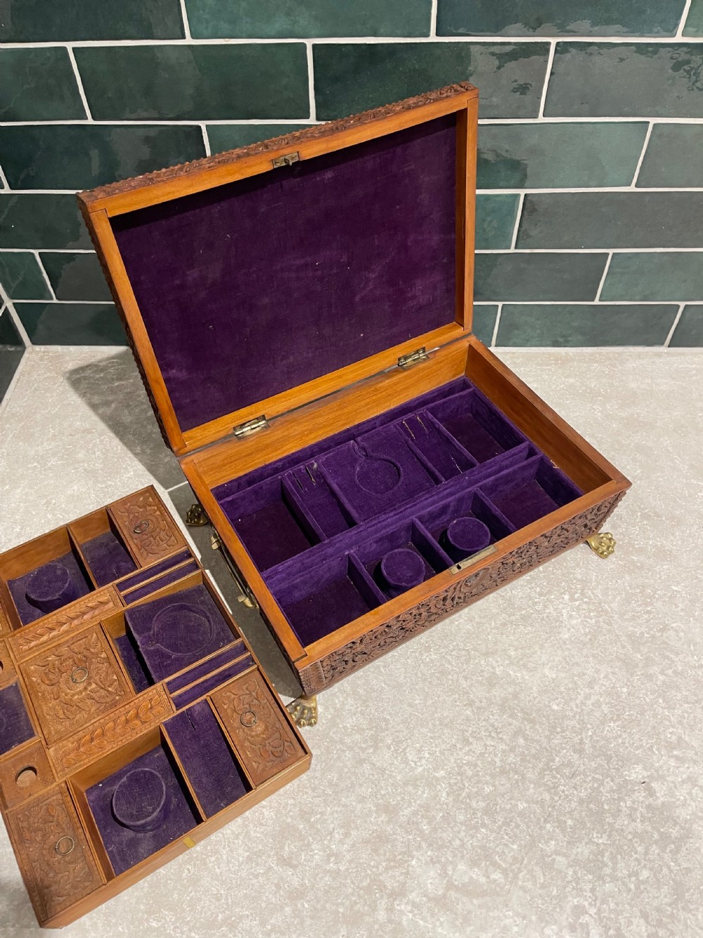 An intricately carved brown sandalwood jewellery box with a stepped lid, brass side drop handles, and brass claw feet. View V