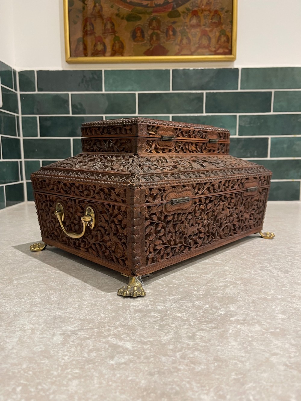 An intricately carved brown sandalwood jewellery box with a stepped lid, brass side drop handles, and brass claw feet. View IX