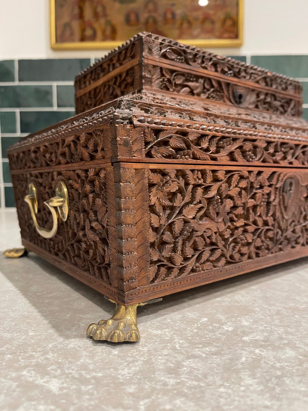 An intricately carved brown sandalwood jewellery box with a stepped lid, brass side drop handles, and brass claw feet. View XI