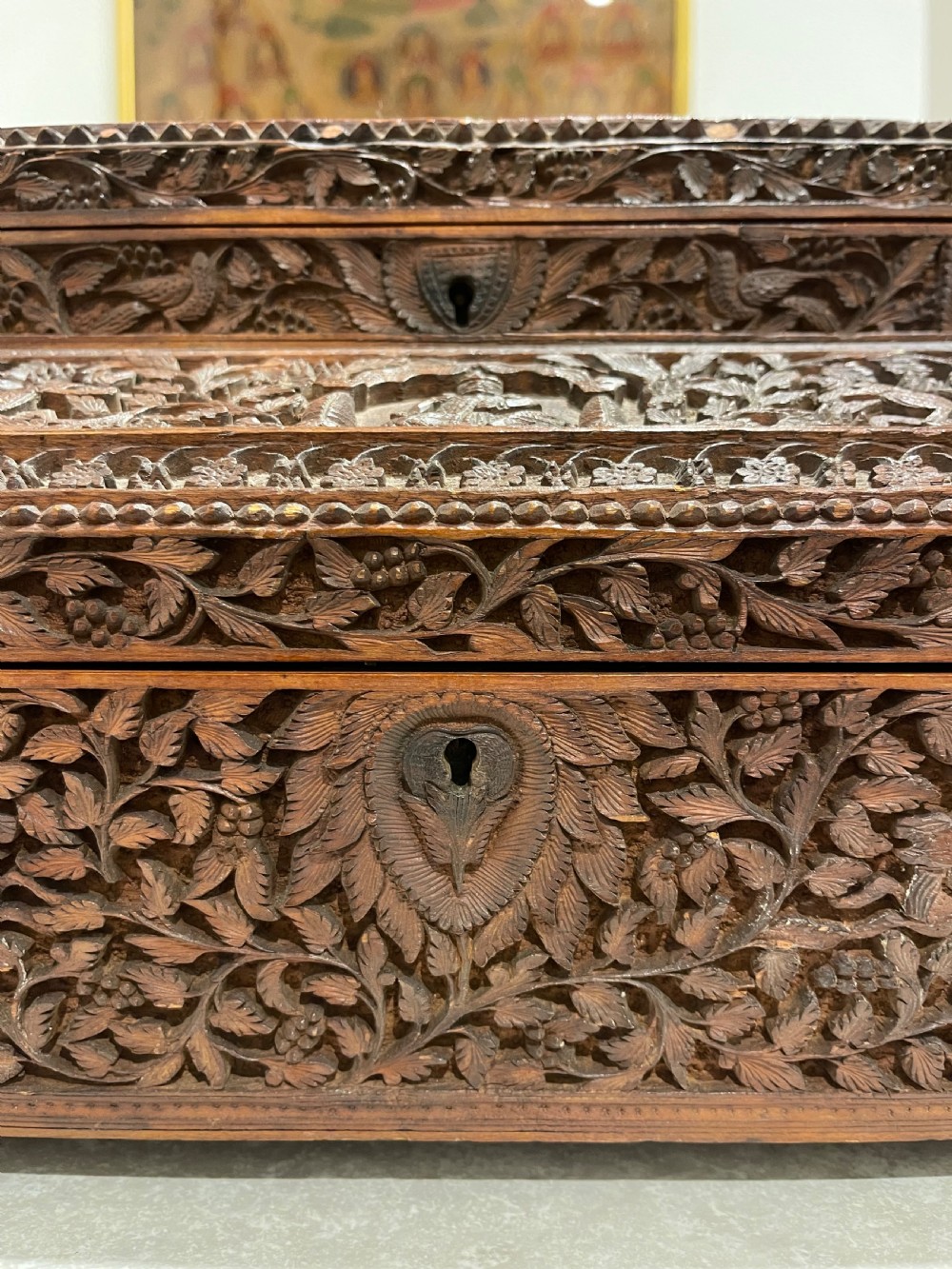An intricately carved brown sandalwood jewellery box with a stepped lid, brass side drop handles, and brass claw feet. View XII