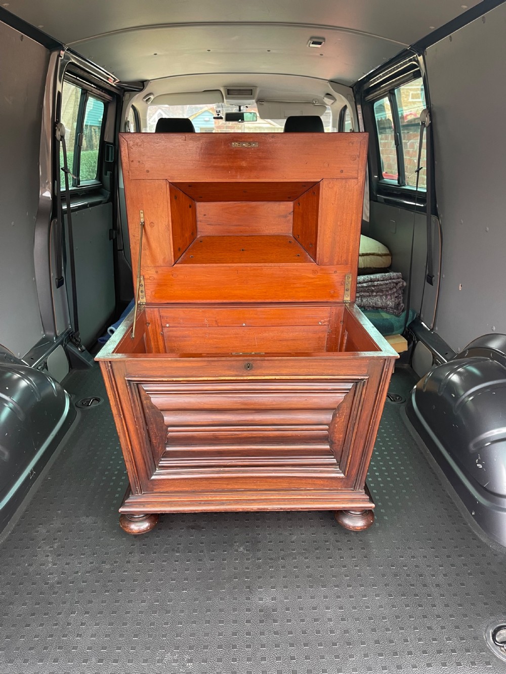 A Regency mahogany cellarette featuring a tapered sarcophagus shape, a hinged lid opening to a hollow interior, ribbed exterior moulding, and turned bun feet.
