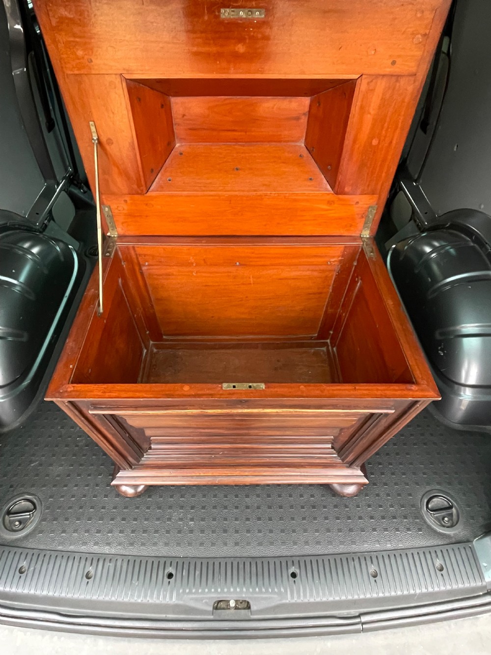 A Regency mahogany cellarette featuring a tapered sarcophagus shape, a hinged lid opening to a hollow interior, ribbed exterior moulding, and turned bun feet. View III