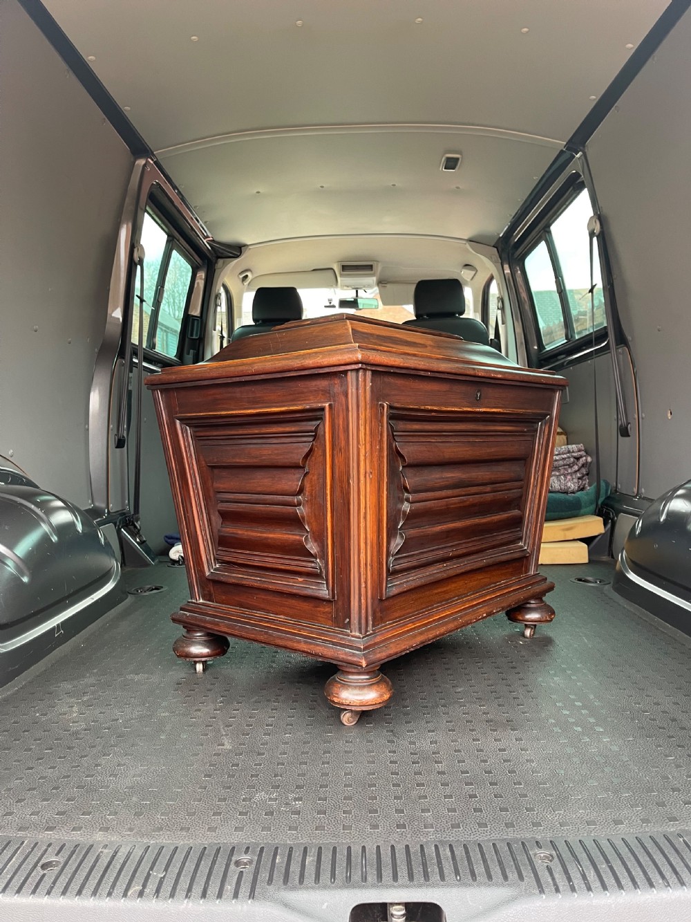 A Regency mahogany cellarette featuring a tapered sarcophagus shape, a hinged lid opening to a hollow interior, ribbed exterior moulding, and turned bun feet. View VI