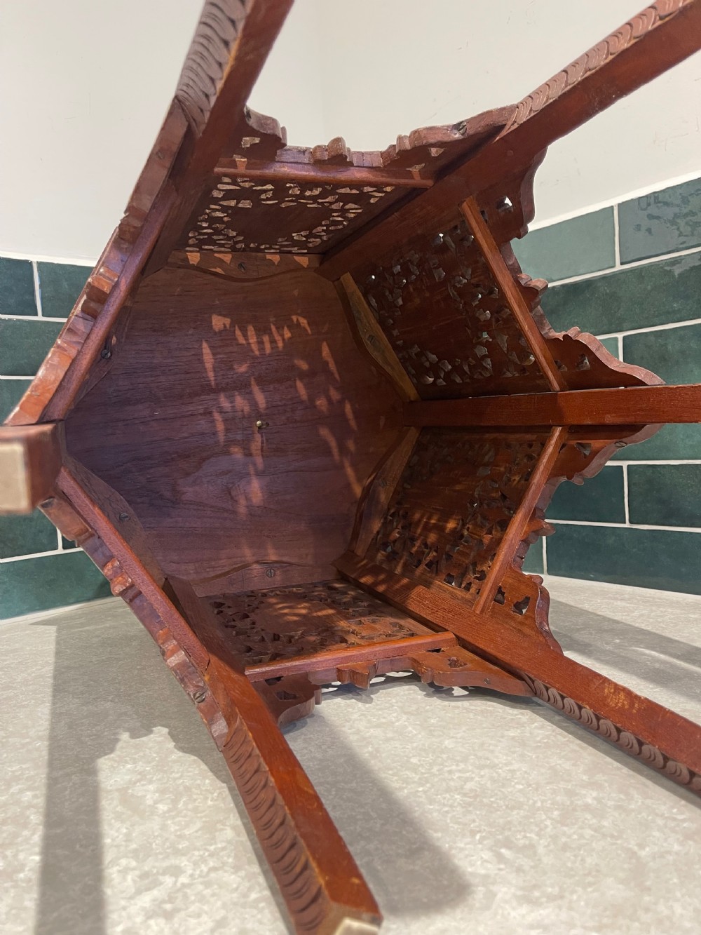 A dark hardwood hexagonal side table featuring intricate hand-carved floral fretwork and pierced side panels with peacock motifs. View V