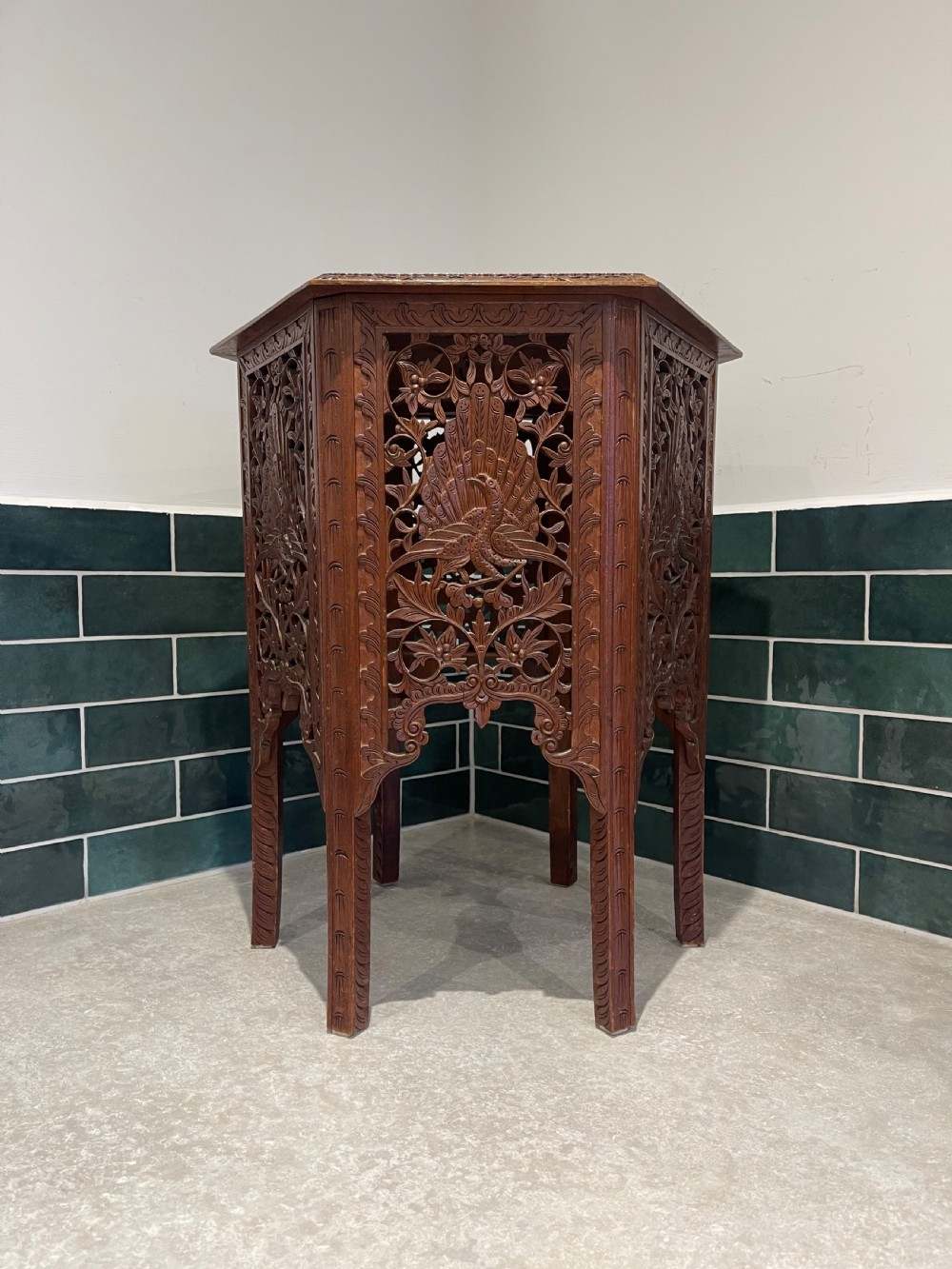A dark hardwood hexagonal side table featuring intricate hand-carved floral fretwork and pierced side panels with peacock motifs. View VI