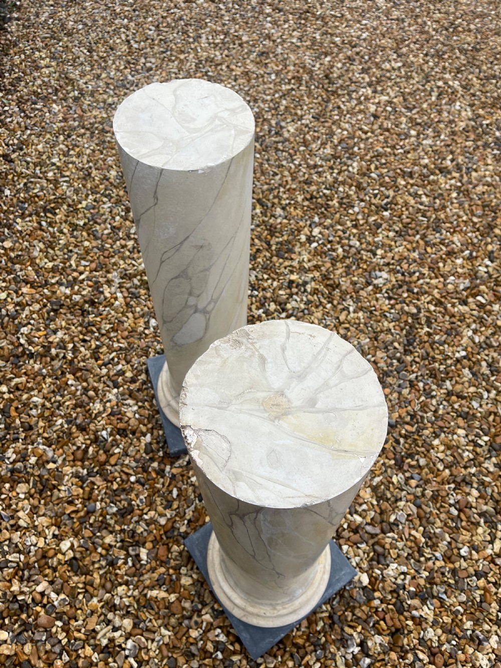 A pair of tall cylindrical plaster pedestals painted with a faux-marble finish on square dark grey plinth bases. View II