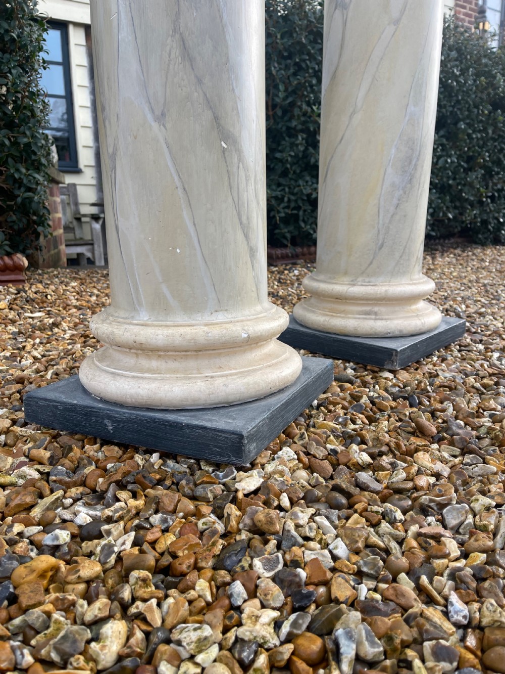 A pair of tall cylindrical plaster pedestals painted with a faux-marble finish on square dark grey plinth bases. View III
