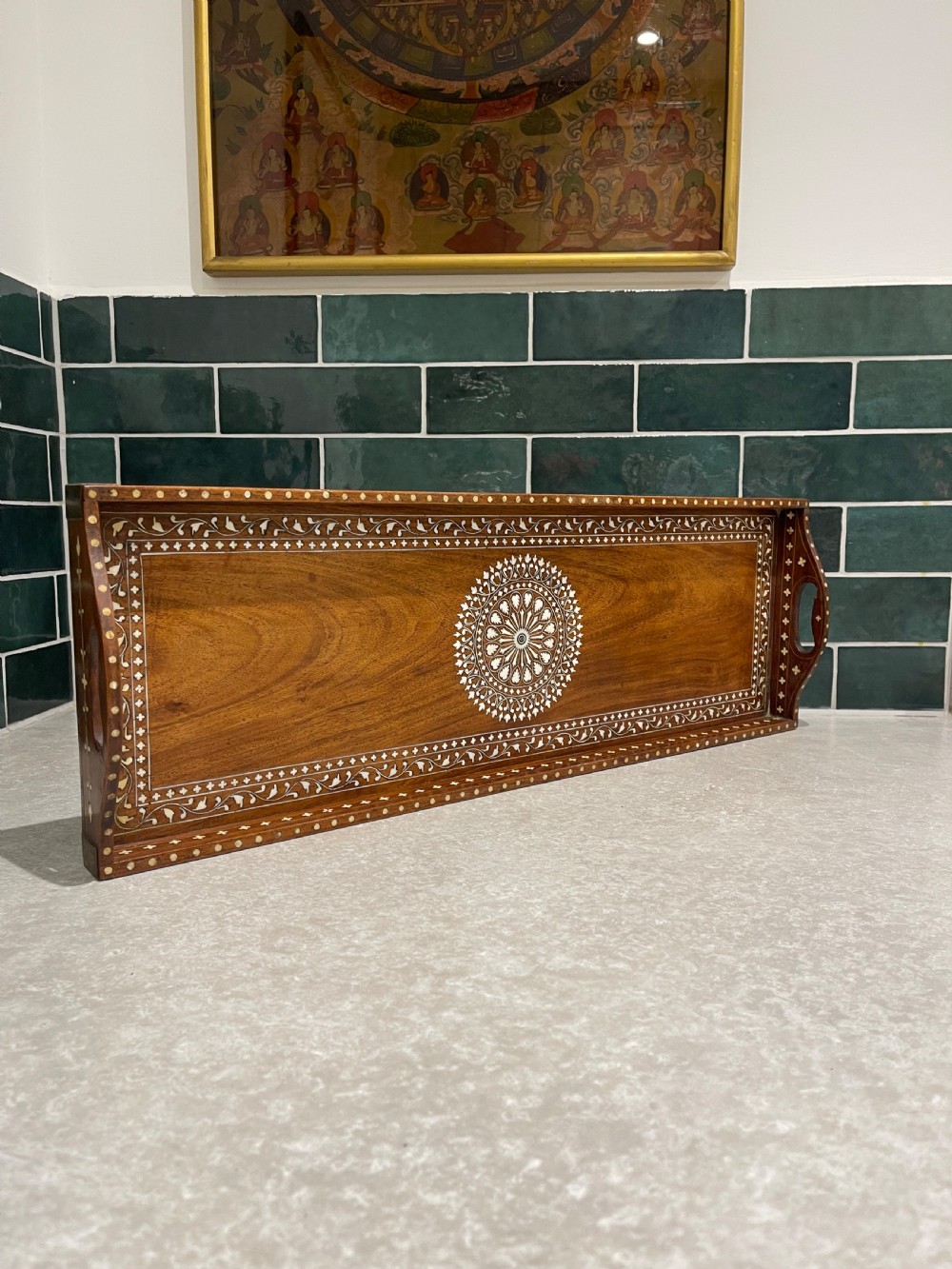 A rectangular warm brown wooden tray featuring intricate white bone inlay in a central floral rosette motif and surrounding foliate borders with cut-out handles.