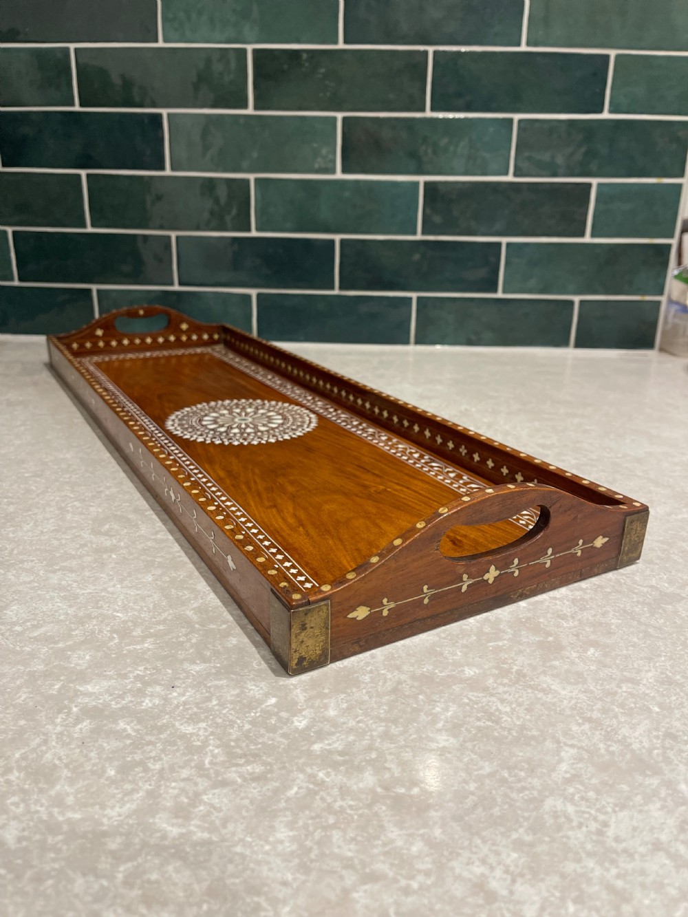 A rectangular warm brown wooden tray featuring intricate white bone inlay in a central floral rosette motif and surrounding foliate borders with cut-out handles. View II