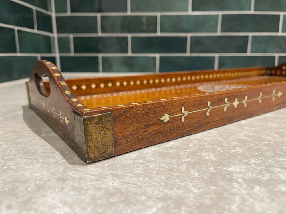 A rectangular warm brown wooden tray featuring intricate white bone inlay in a central floral rosette motif and surrounding foliate borders with cut-out handles. View VI