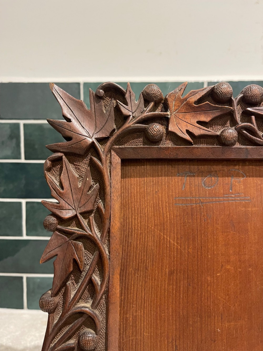 A hand-carved dark walnut picture frame featuring a relief border of chinar leaves and seed pods against a textured stippled background. View IV