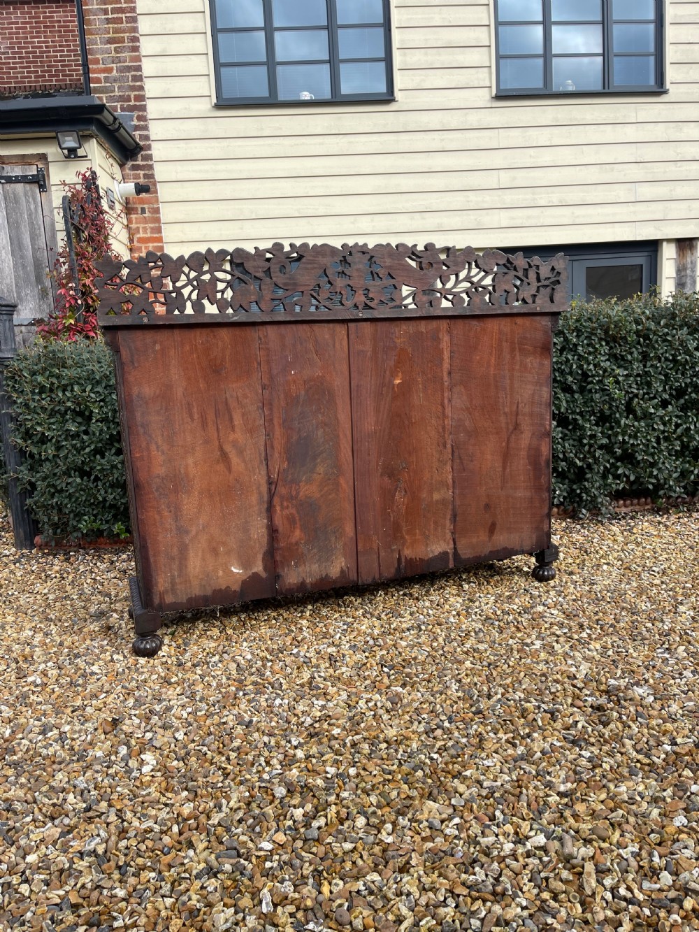 A dark carved padauk sideboard featuring four pierced floral fretwork doors, a carved gallery backrest, and bun feet. View VI