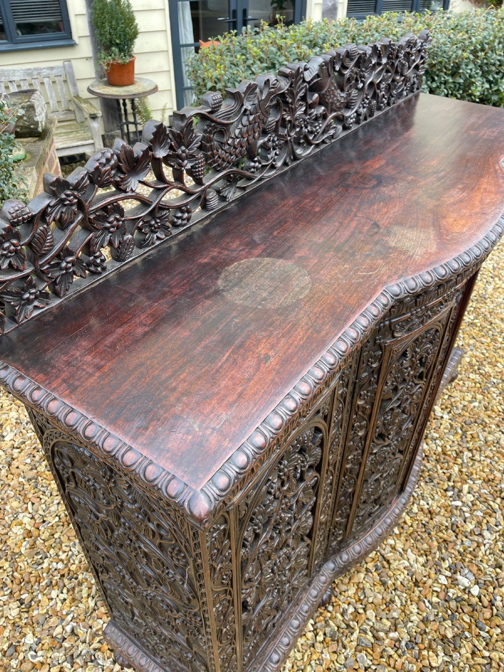 A dark carved padauk sideboard featuring four pierced floral fretwork doors, a carved gallery backrest, and bun feet. View VIII