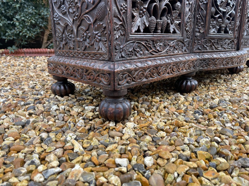 A dark carved padauk sideboard featuring four pierced floral fretwork doors, a carved gallery backrest, and bun feet. View IX