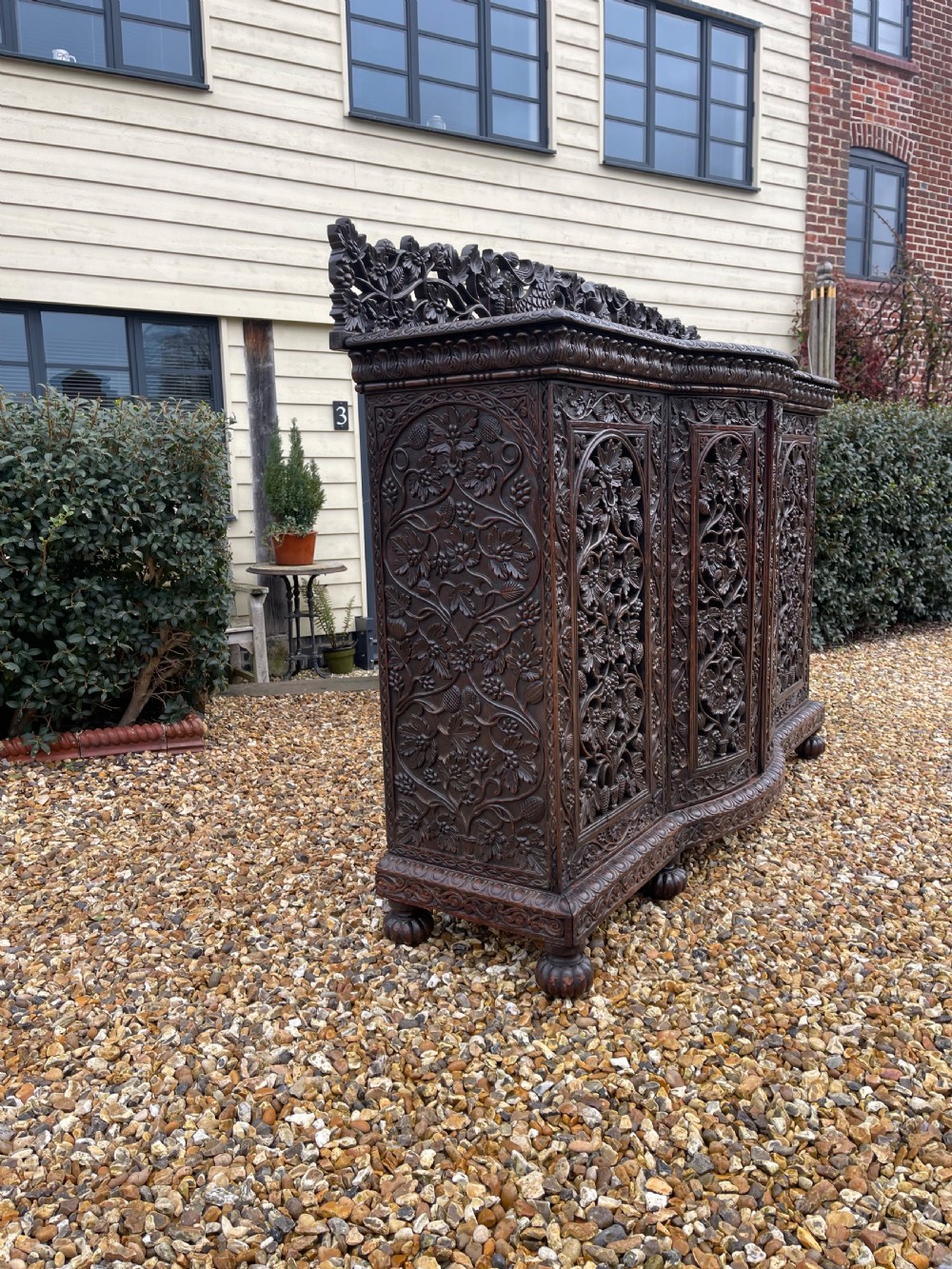 A dark carved padauk sideboard featuring four pierced floral fretwork doors, a carved gallery backrest, and bun feet. View XI