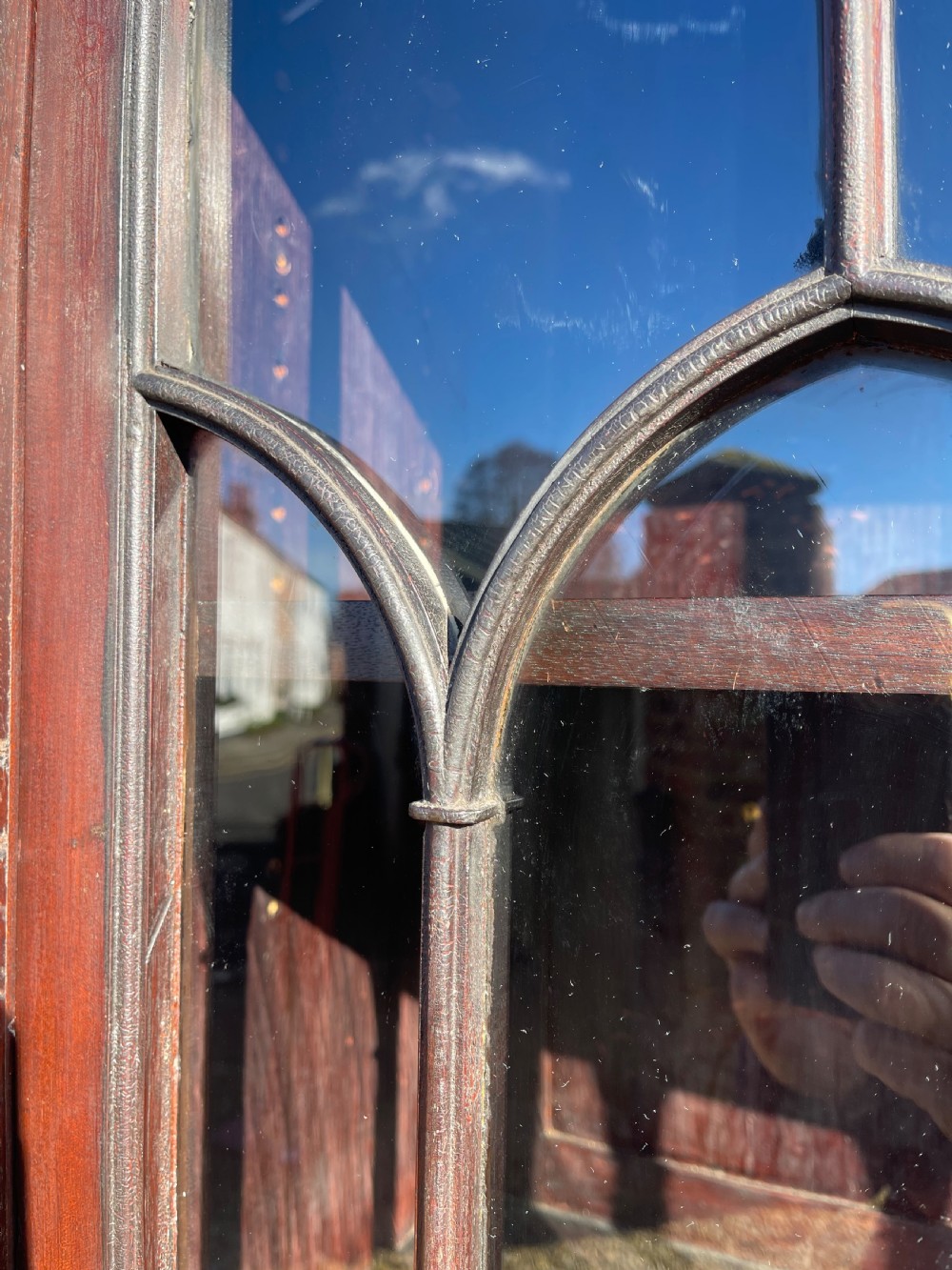 A tall dark mahogany two-door glazed bookcase featuring a concave front facade and gothic pointed arch glazing bars. View IV