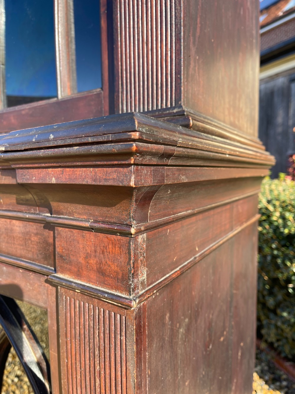 A tall dark mahogany two-door glazed bookcase featuring a concave front facade and gothic pointed arch glazing bars. View V