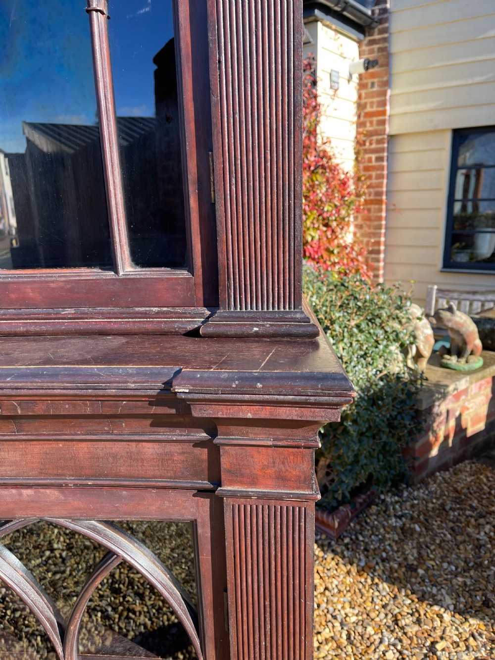 A tall dark mahogany two-door glazed bookcase featuring a concave front facade and gothic pointed arch glazing bars. View VI