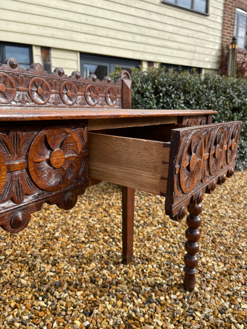 A Victorian oak hall table featuring a carved rosette gallery back, decorative apron, and front bobbin-turned legs. View II