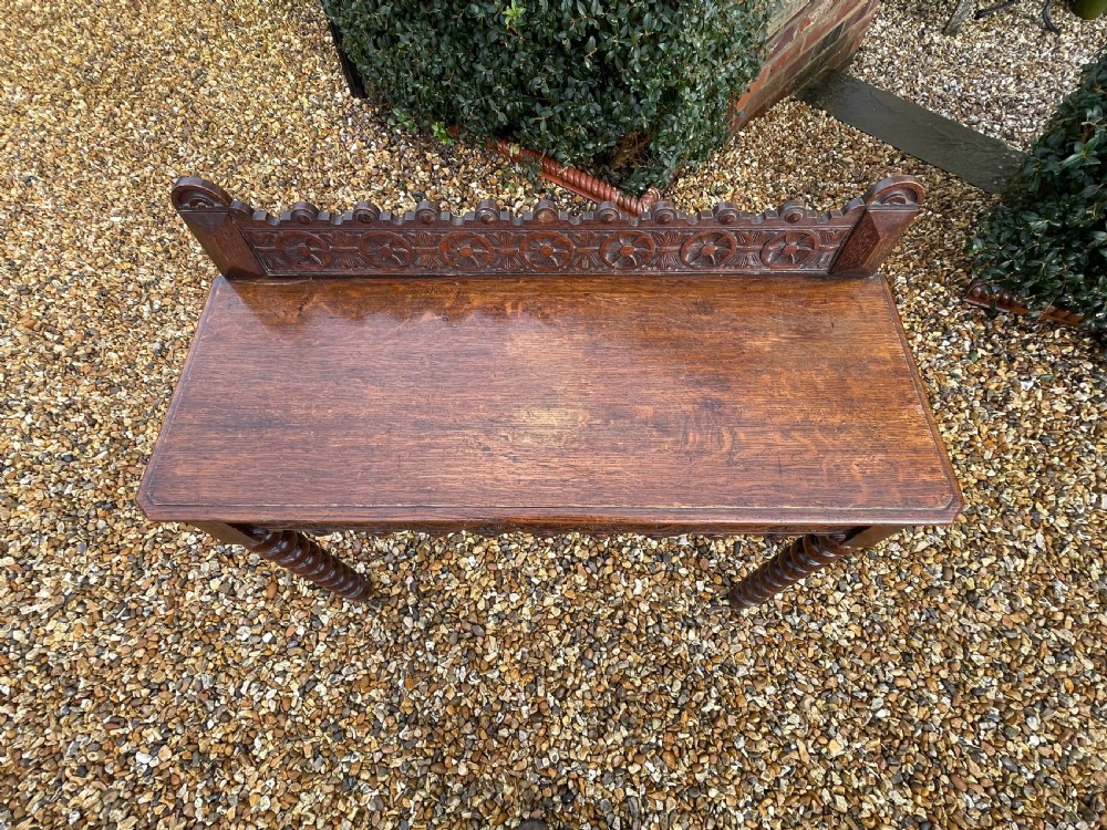 A Victorian oak hall table featuring a carved rosette gallery back, decorative apron, and front bobbin-turned legs. View IV