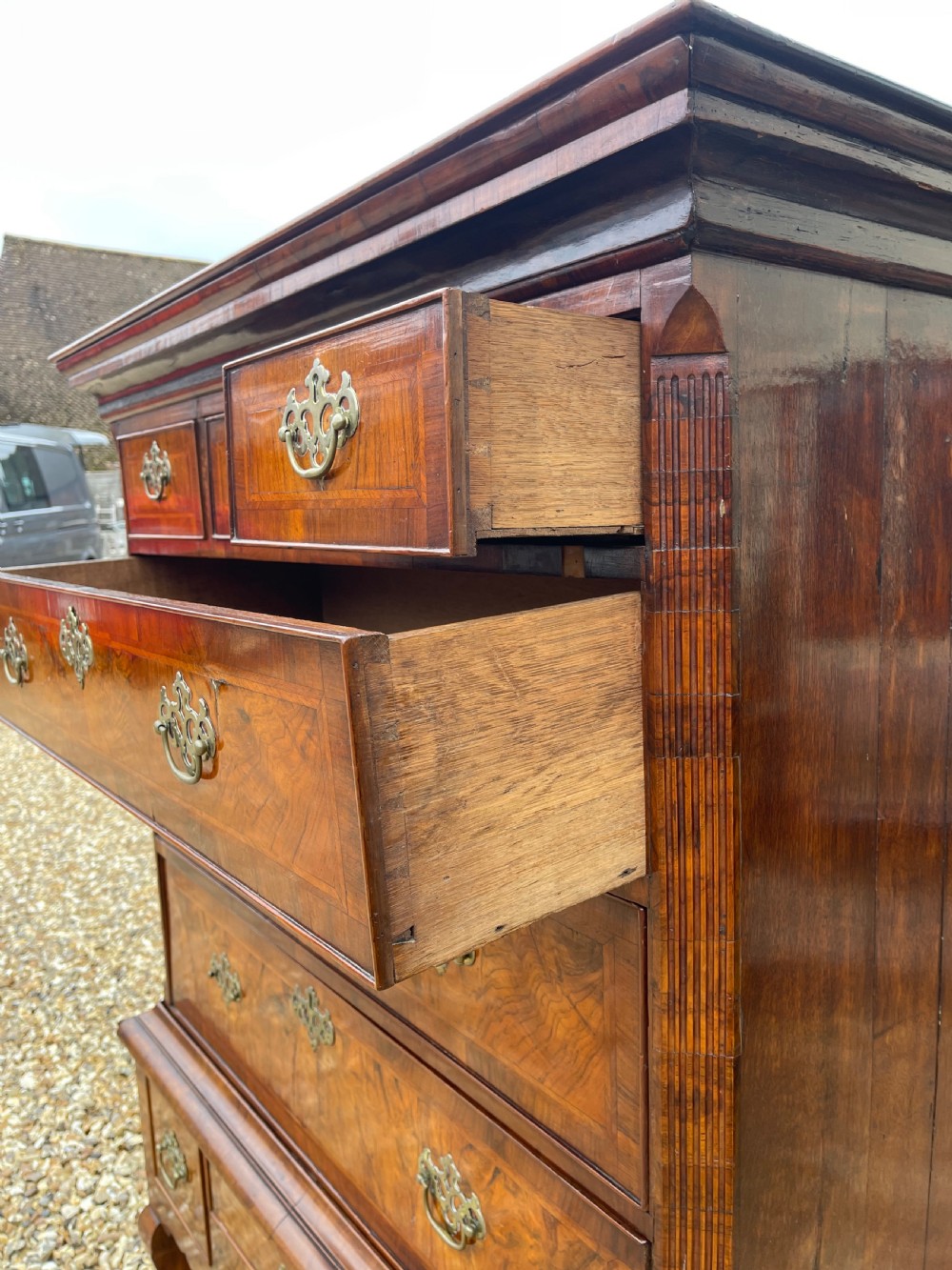 An 18th-century walnut chest on stand featuring crossbanded drawer fronts, brass batwing drop handles, a shaped apron, and cabriole legs. View IV