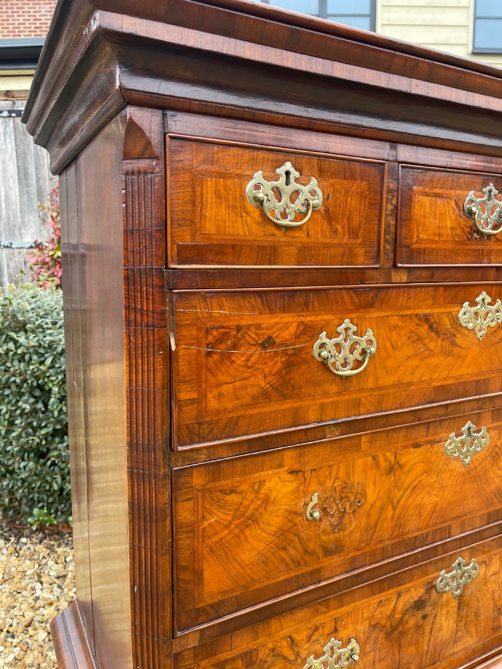 An 18th-century walnut chest on stand featuring crossbanded drawer fronts, brass batwing drop handles, a shaped apron, and cabriole legs. View V