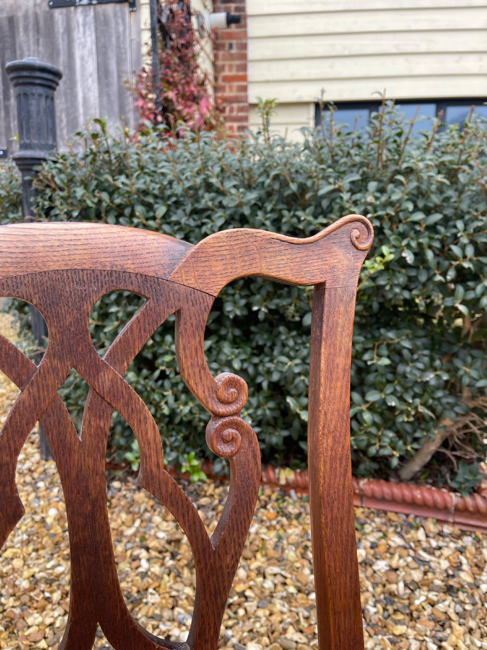 A pair of dark oak antique side chairs with intricately carved openwork back splats and tan upholstered seats. View II