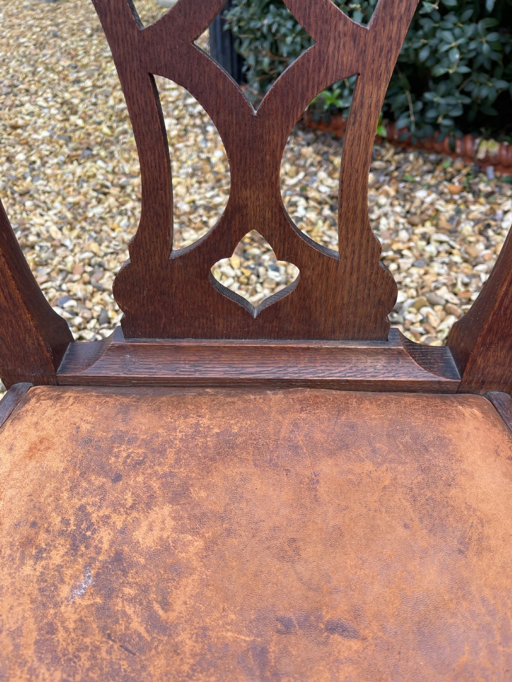 A pair of dark oak antique side chairs with intricately carved openwork back splats and tan upholstered seats. View III