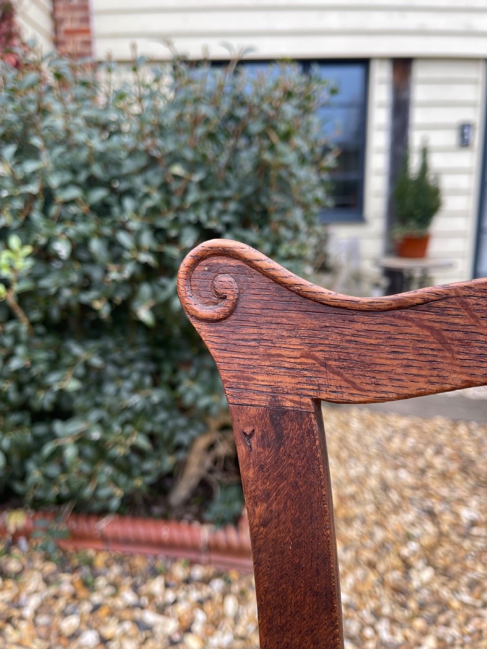 A pair of dark oak antique side chairs with intricately carved openwork back splats and tan upholstered seats. View V