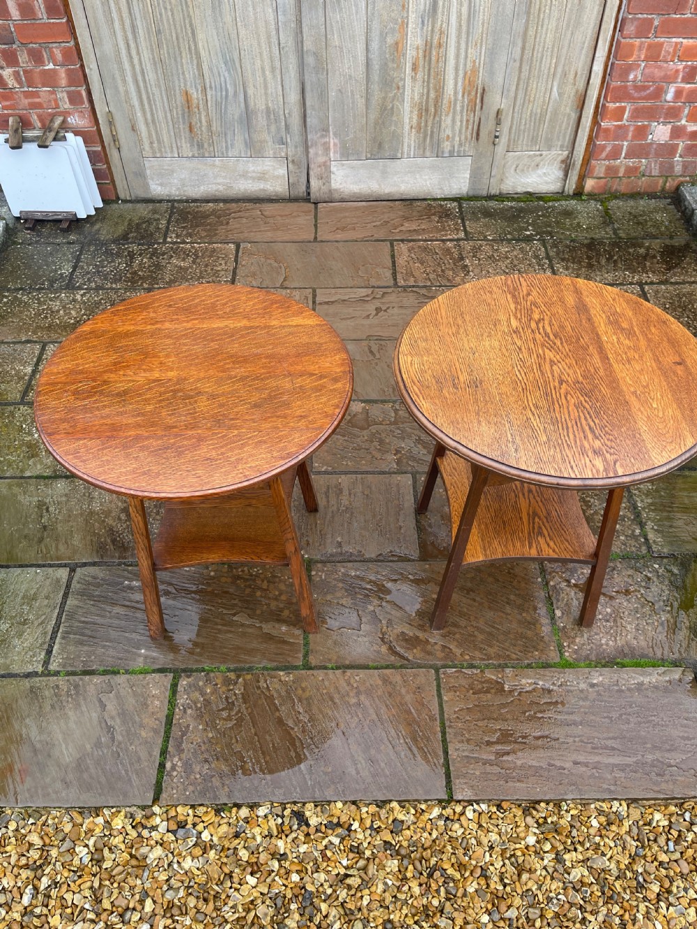 A pair of matching Arts and Crafts style oak side tables with circular tops, pierced heart motif friezes, and lower undertier shelves. View II