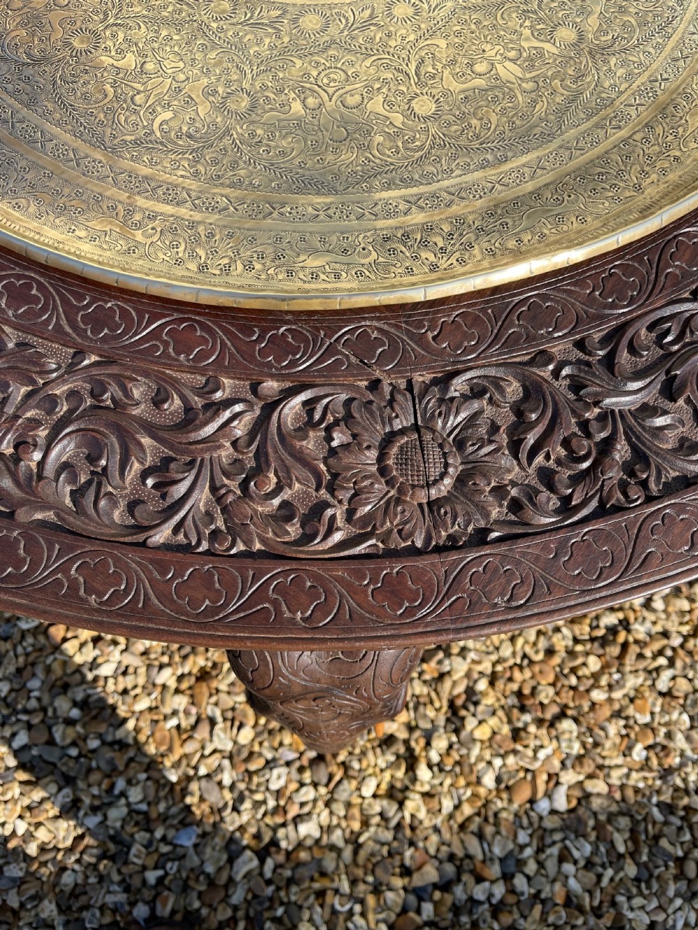 A circular carved dark wood table featuring legs shaped as elephant heads with tusks and an inset circular engraved brass tray in the centre. View III
