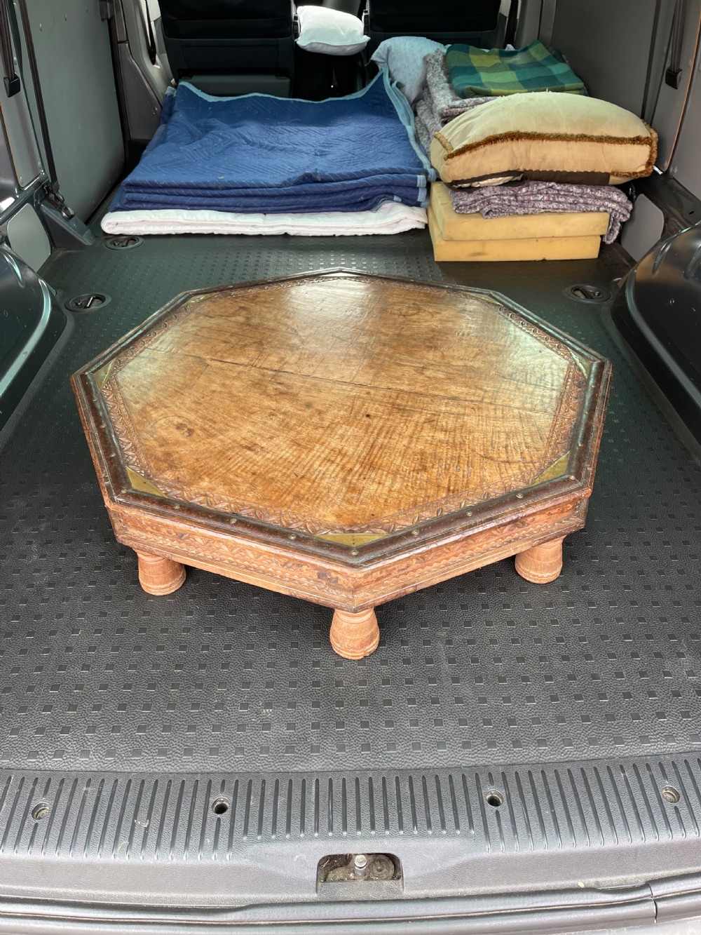 A nineteenth-century octagonal Indian low wooden table featuring intricate carved edges, metal corner reinforcement plates, and four short turned legs.