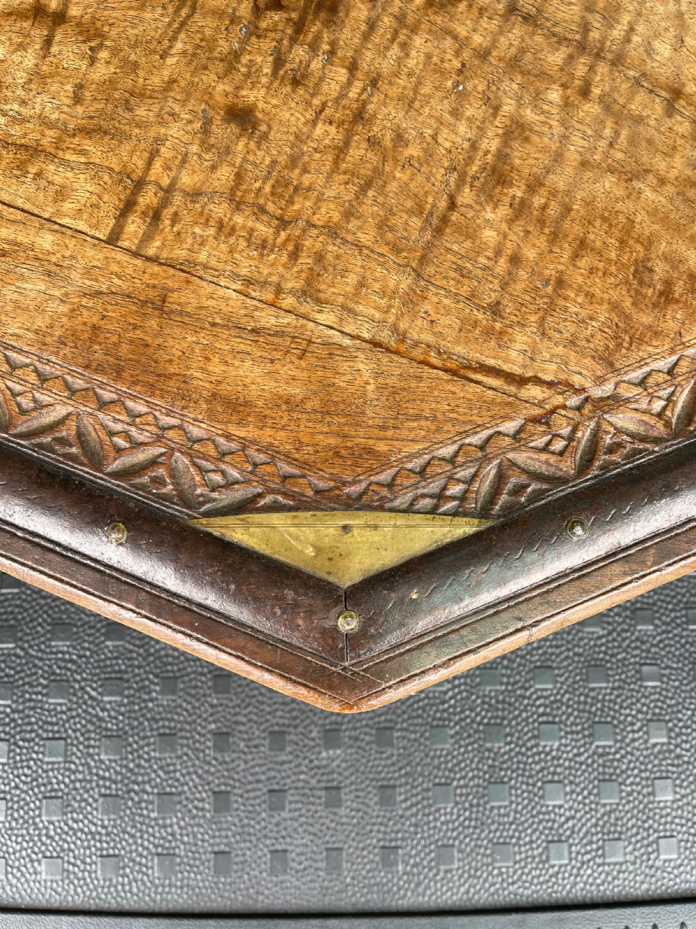 A nineteenth-century octagonal Indian low wooden table featuring intricate carved edges, metal corner reinforcement plates, and four short turned legs. View V
