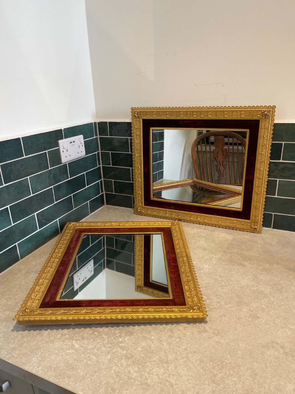 A pair of nineteenth-century rectangular mirrors featuring gold gilt frames decorated with leaf mouldings and lined with inner borders of crimson red velvet.