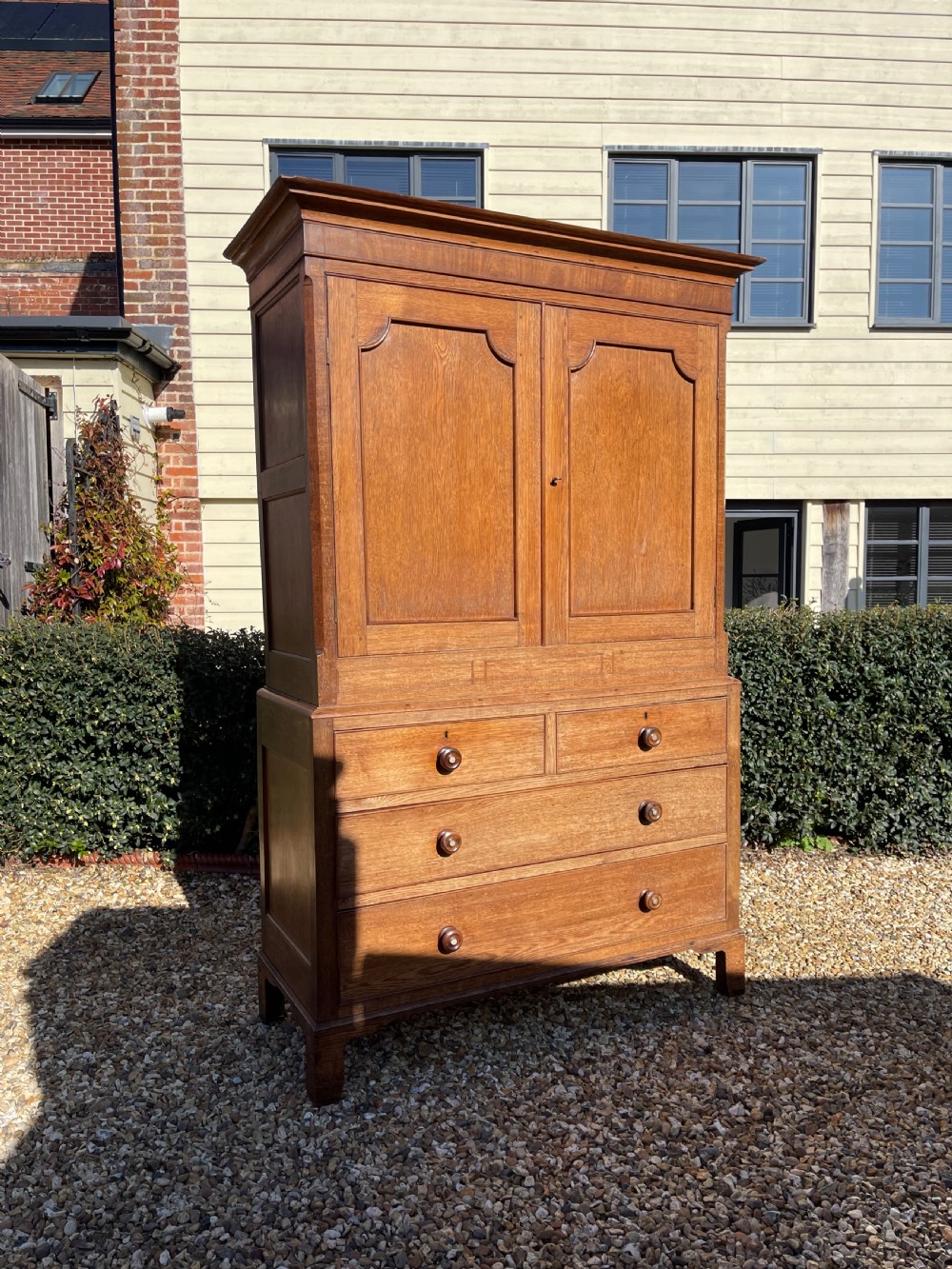 A nineteenth-century Welsh oak press cupboard featuring an upper double-door section with arched fielded panels over a base with four drawers.