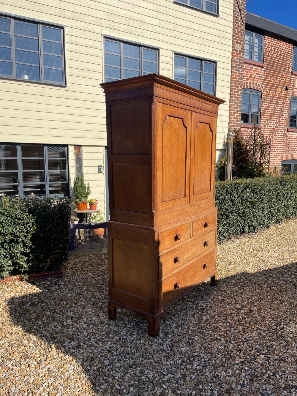A nineteenth-century Welsh oak press cupboard featuring an upper double-door section with arched fielded panels over a base with four drawers. View V