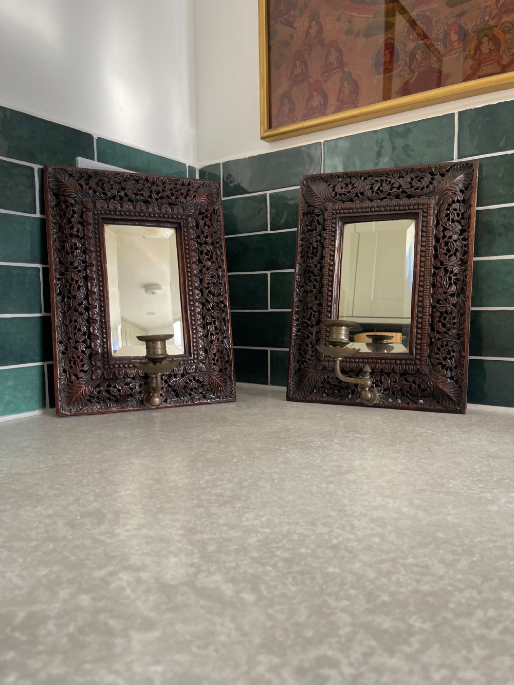 A pair of rectangular dark carved hardwood wall sconces featuring intricate floral openwork frames, inset rectangular mirrors, and central brass candle arms.