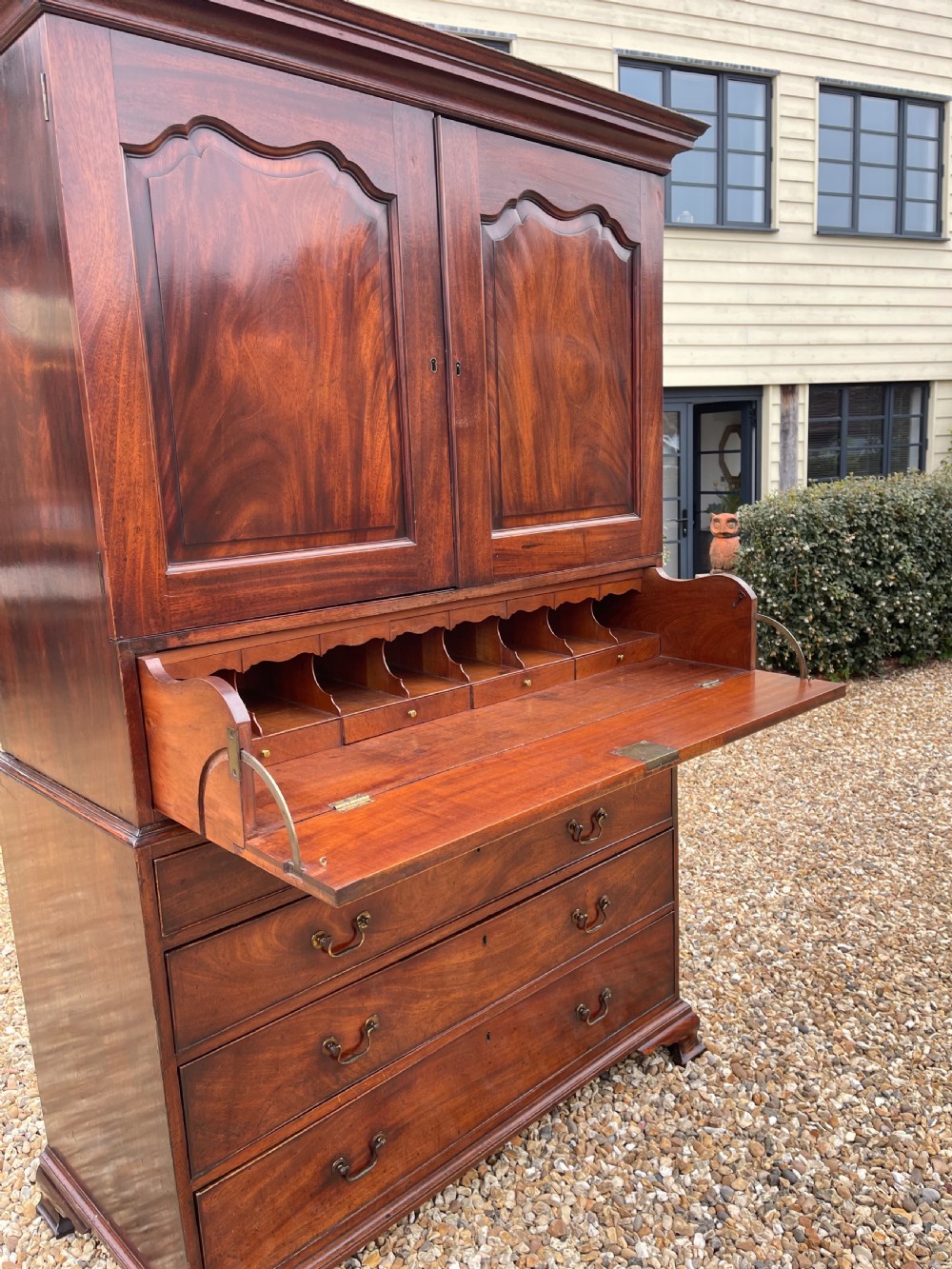 A tall Georgian mahogany secretaire press cupboard featuring two panelled doors above drawers with brass handles, resting on bracket feet. View X