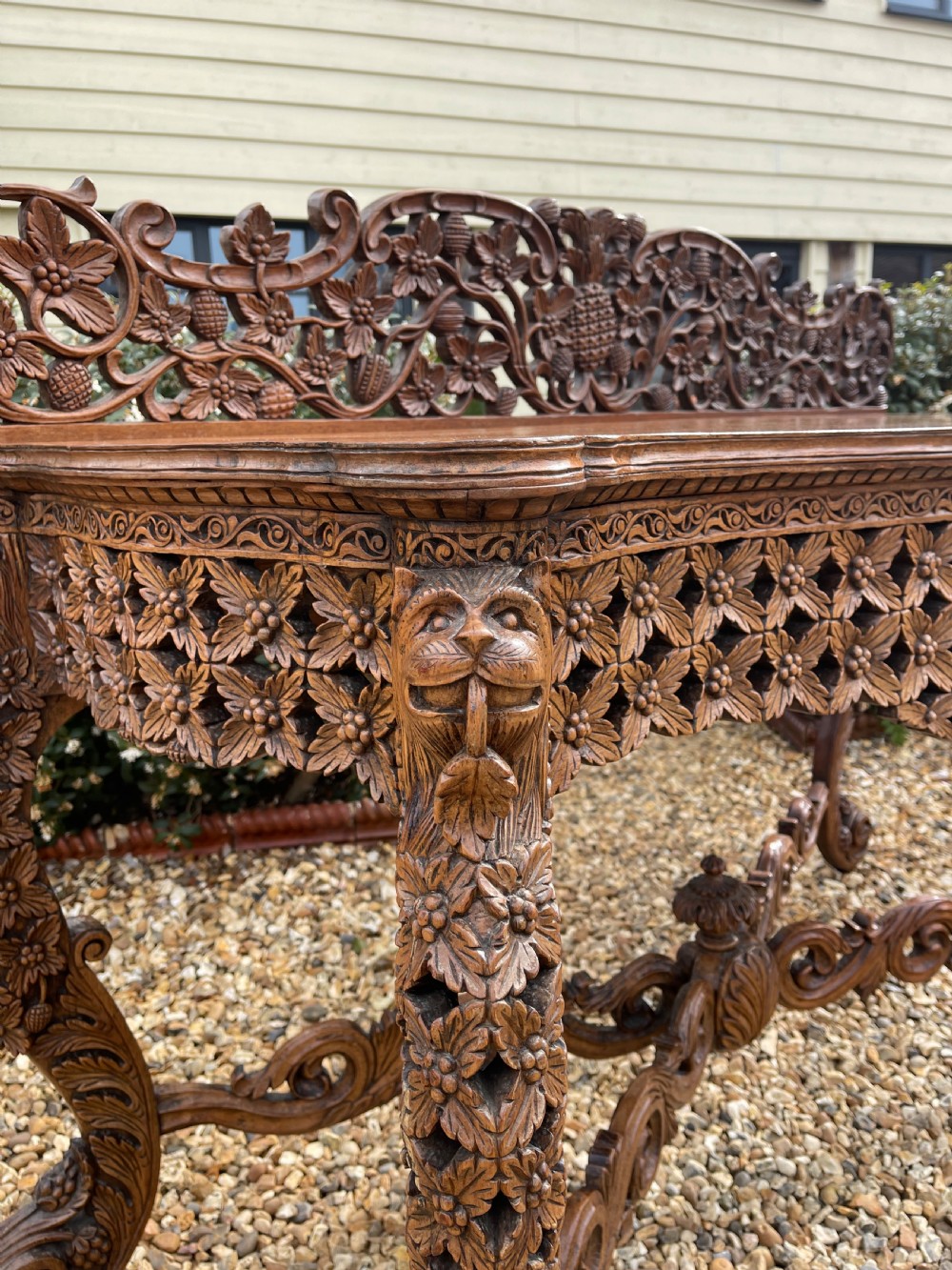 A nineteenth-century Anglo-Indian carved wood console table featuring a detailed openwork apron, gallery back, and intricately carved leg supports. View VI