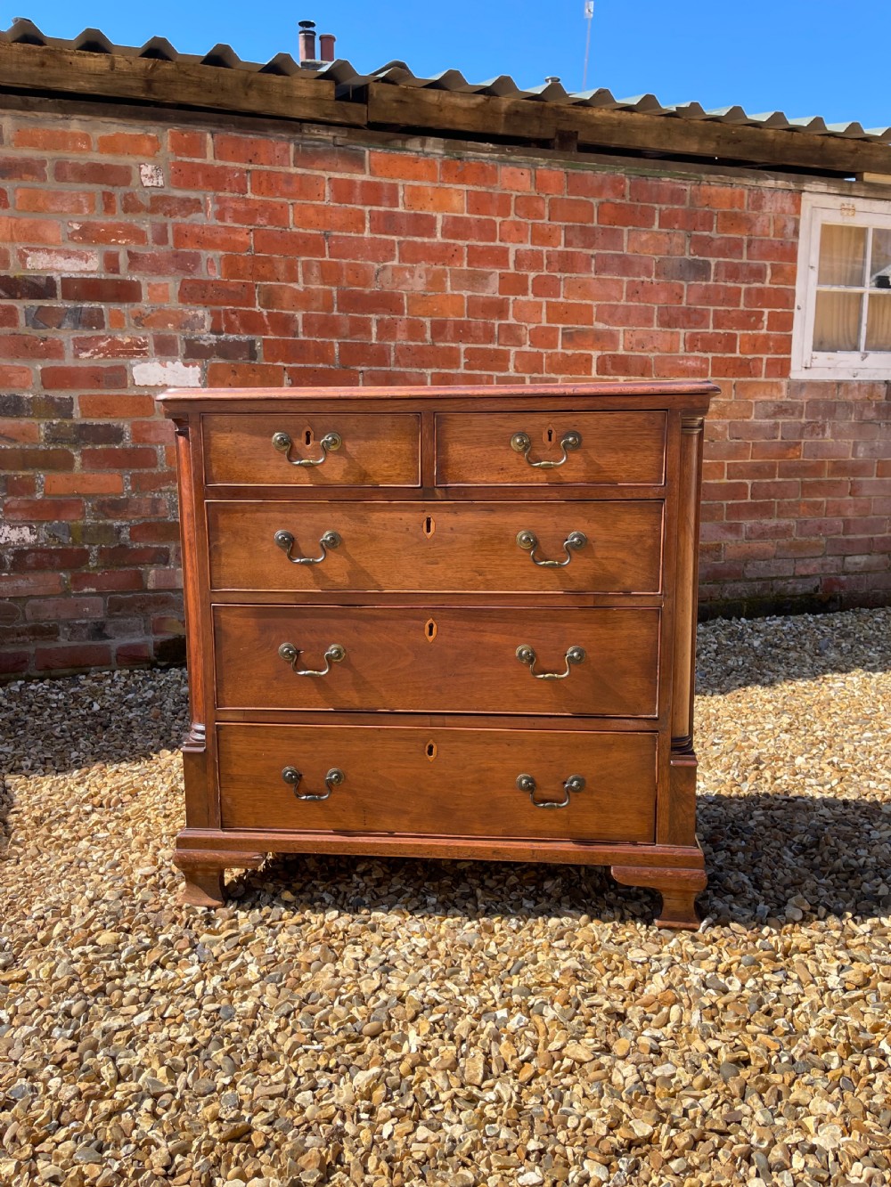 An eighteenth-century Georgian mahogany chest of drawers featuring two short drawers over three long drawers, finished with brass swan-neck handles and bracket feet.